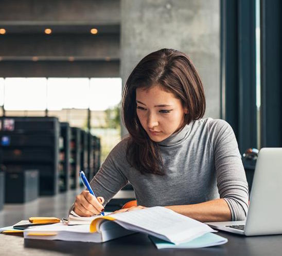 Woman studying Excel course materials with laptop.